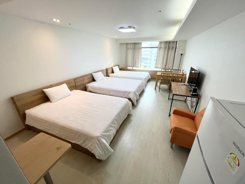 仁川にあるIncheon Airport Guesthouseのベッド2台とテーブルが備わるホテルルームです。