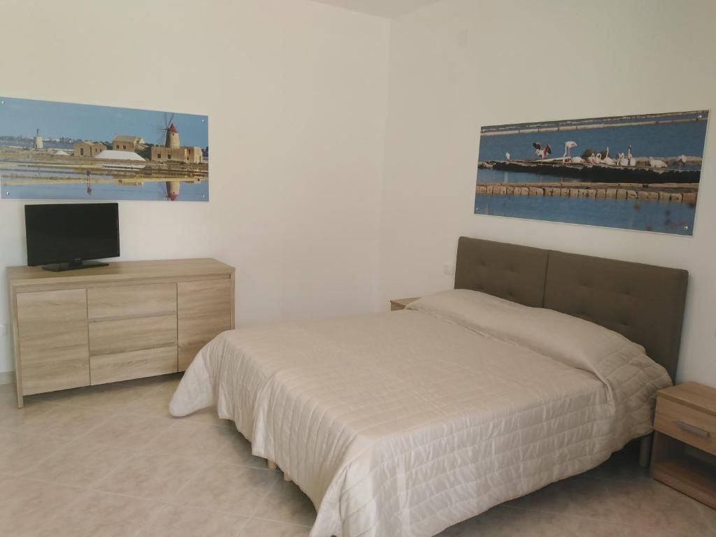 um quarto com uma cama, uma televisão e um quadro em SALINA APPARTAMENTI em Trapani