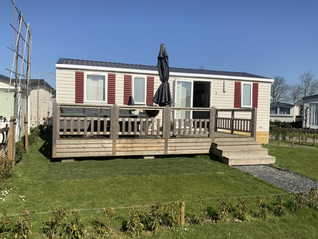 una casa con una terraza con una sombrilla en Chalet Zonnig Zeeland en Oostkapelle