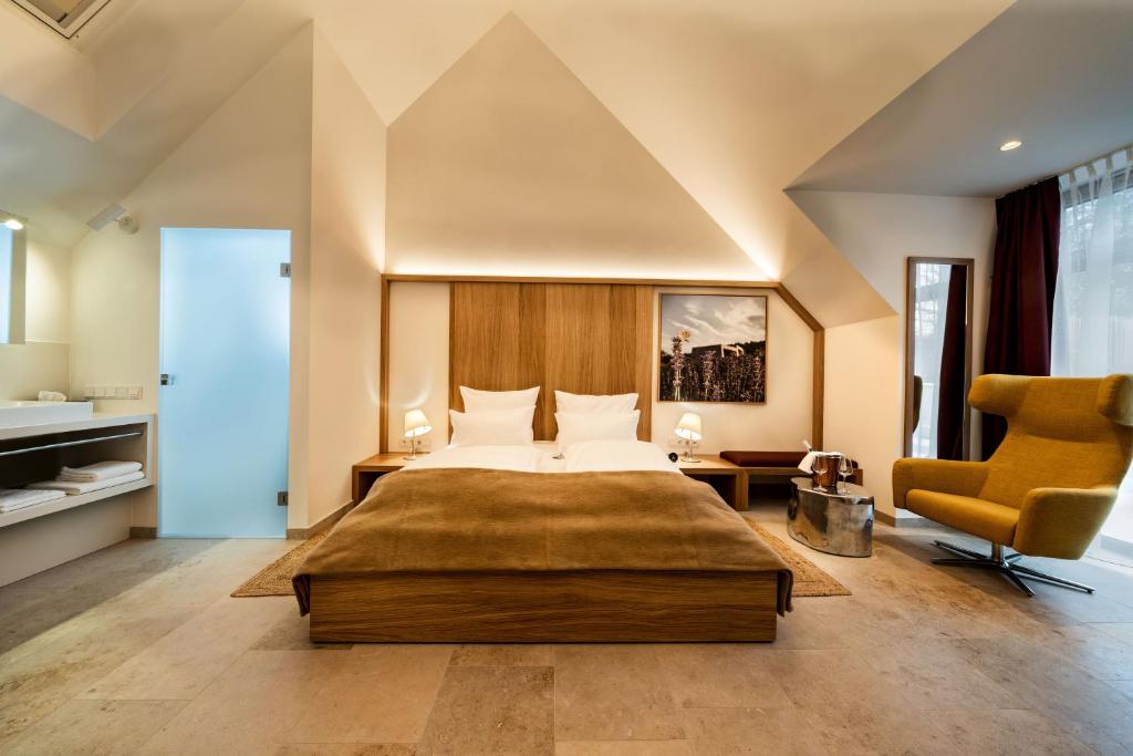 ein Schlafzimmer mit einem großen Bett und einem gelben Stuhl in der Unterkunft Flora auf Gut Guntrams in Schwarzau am Steinfelde