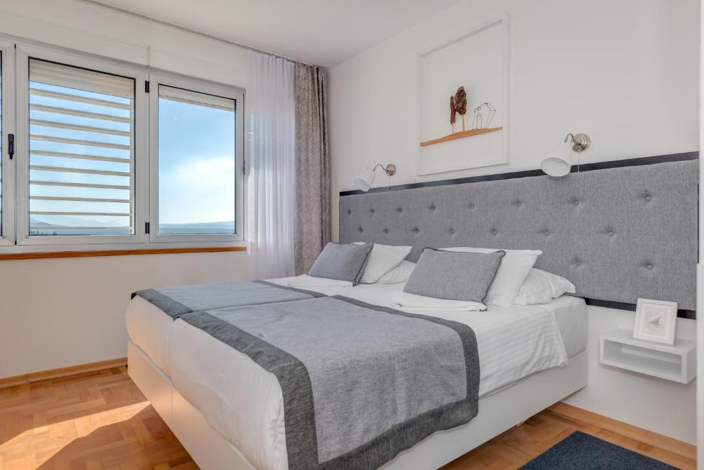 a white bedroom with a large bed and a window at Hotel Pax in Split