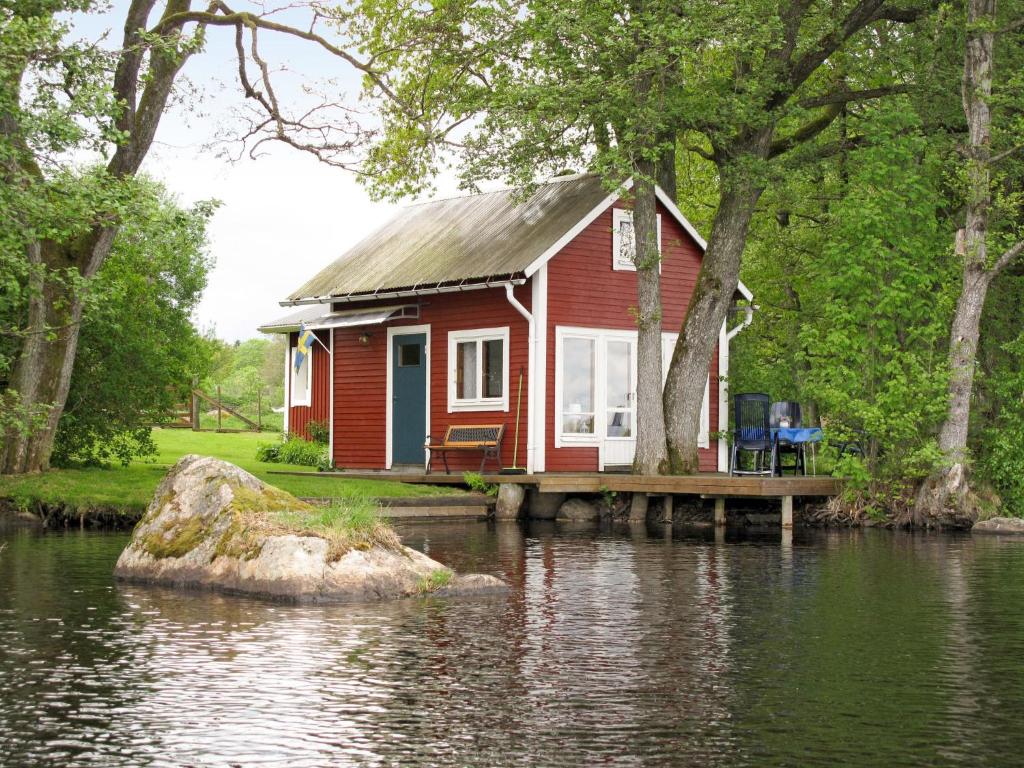 una casa roja en un muelle sobre un cuerpo de agua en Holiday Home Sjöatorp Sjöstugan by Interhome, en Hjortsberga