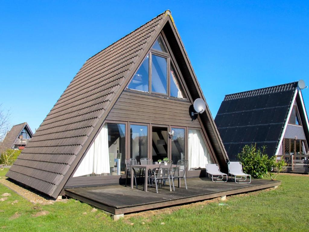 a house with a gambrel roof with a table and chairs at Holiday Home Fedderwardersiel-5 by Interhome in Fedderwarderdeich