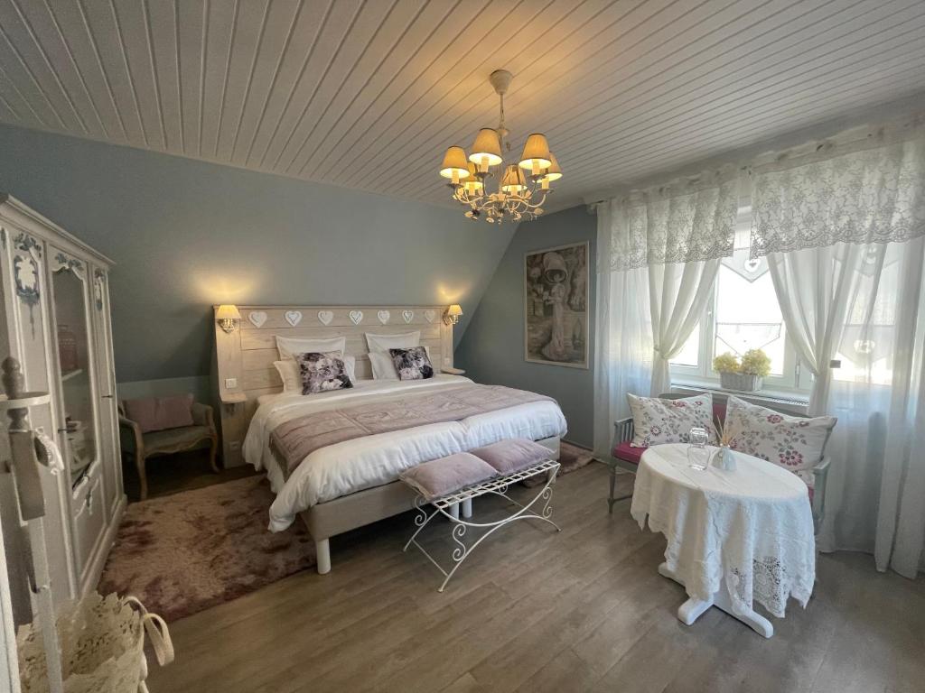 a bedroom with a bed and a table and a chandelier at Gite Riquewihr "C'est Beau la Vie Alsace" in Riquewihr