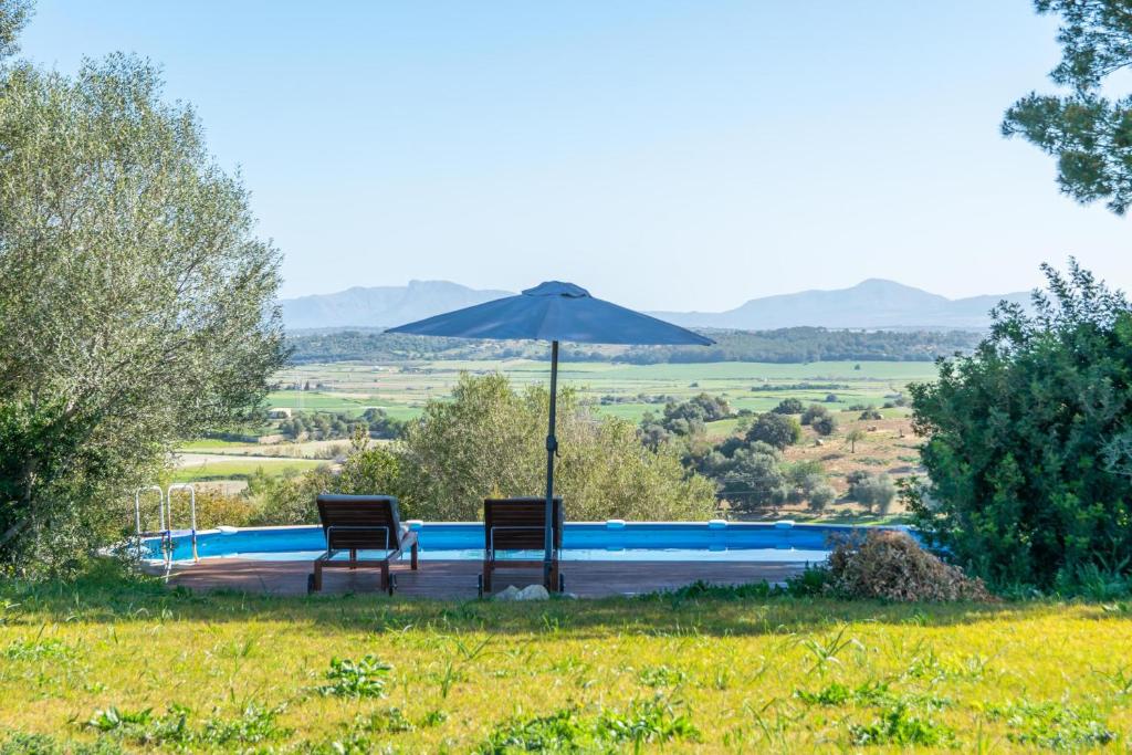 zwei Stühle und ein Sonnenschirm neben einem Pool in der Unterkunft Can Grever in Llubí