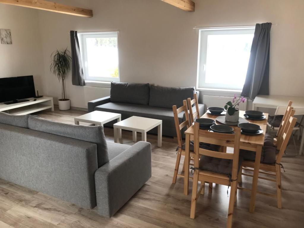 uma sala de estar com um sofá, uma mesa e cadeiras em Apartmány PRO LIPNO em Horní Planá