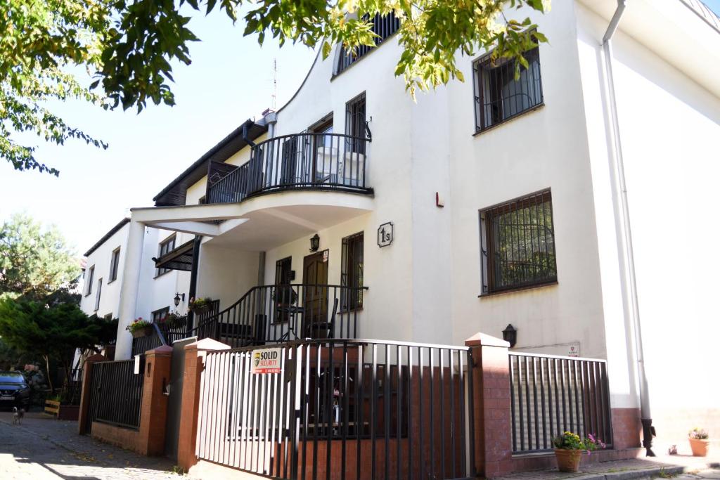 a white building with black balconies and a fence at Hotel-hostel Saska in Warsaw