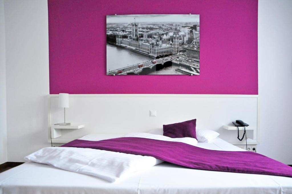 a bedroom with a purple painting above a bed at Hotel zum Brunnen in Friedberg