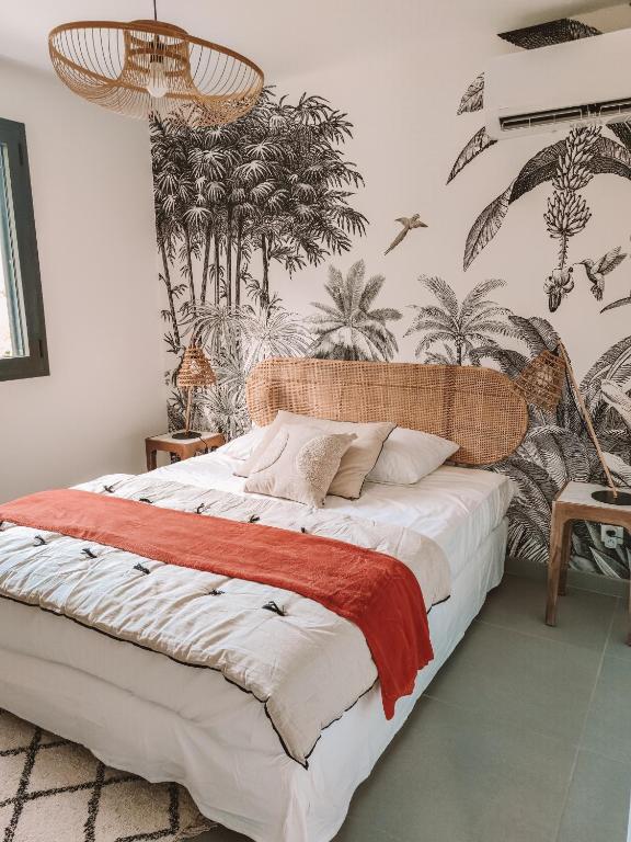 a bedroom with a large bed with palm trees on the wall at Les Villas Mandju in Sainte-Rose