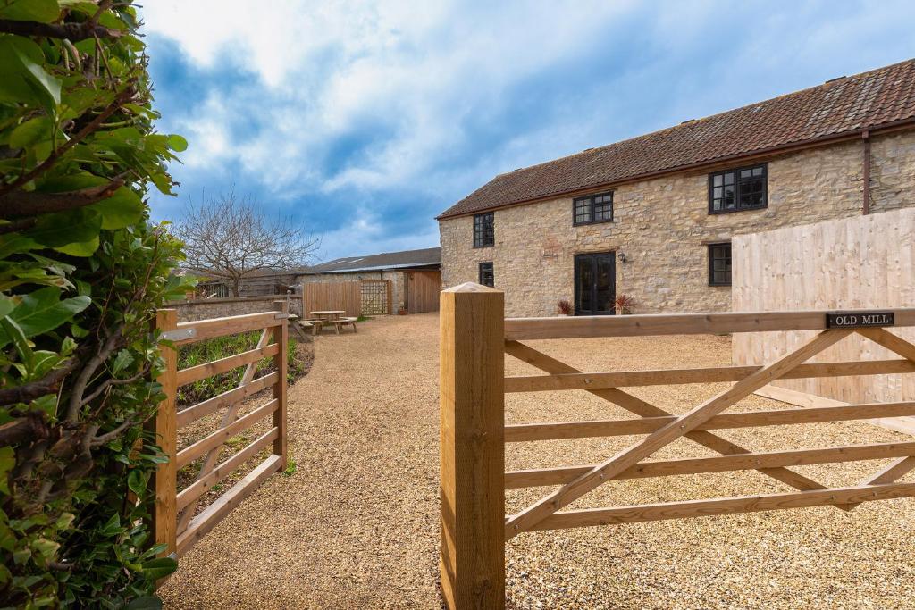 une clôture en bois devant une grange dans l'établissement Somerset Country Escape - Luxury barns with hot tubs, à Hatch Beauchamp