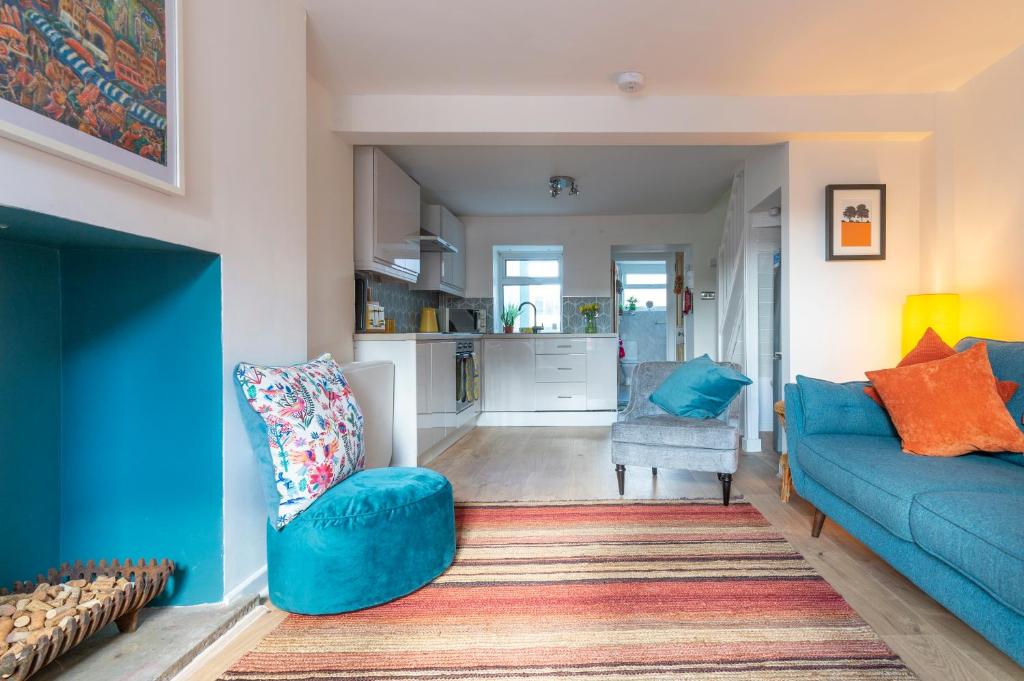 a living room with a blue couch and a kitchen at Hare Cottage in Abergavenny