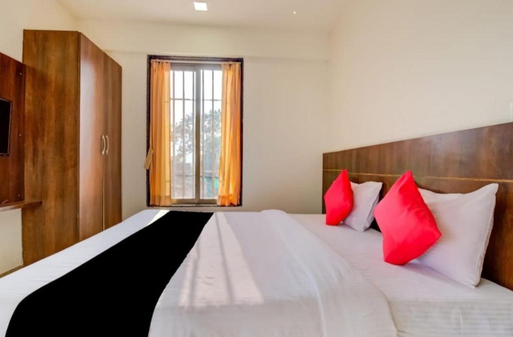 a bedroom with a large white bed with red pillows at Hotel rio inn in Trimbak