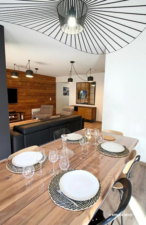 une table de salle à manger avec des assiettes et des verres dessus dans l'établissement Magnifique T5 Duplex de Grand Standing 120m2 neuf classé 4 étoiles pour 8 personnes en plein centre de Saint-Lary-Soulan, à Saint-Lary-Soulan