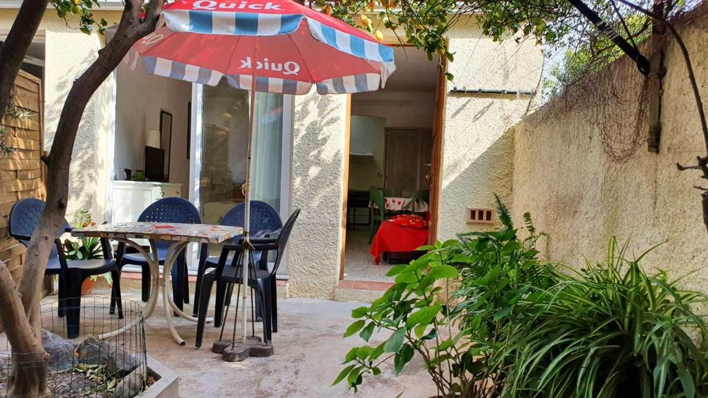 een patio met een tafel en stoelen en een parasol bij Studio a Banyuls sur Mer a 300 m de la plage avec terrasse amenagee et wifi in Banyuls-sur-Mer