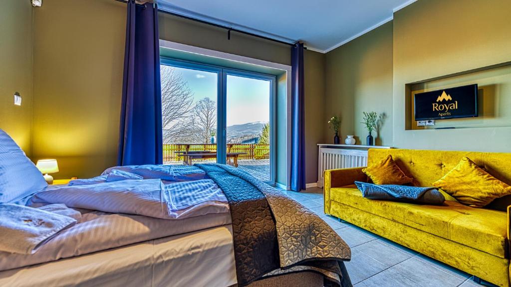 sypialnia z dużym łóżkiem i żółtą kanapą w obiekcie Apartamenty ROYAL APARTS Zielona Poręba - z panoramą gór w Szklarskiej Porębie
