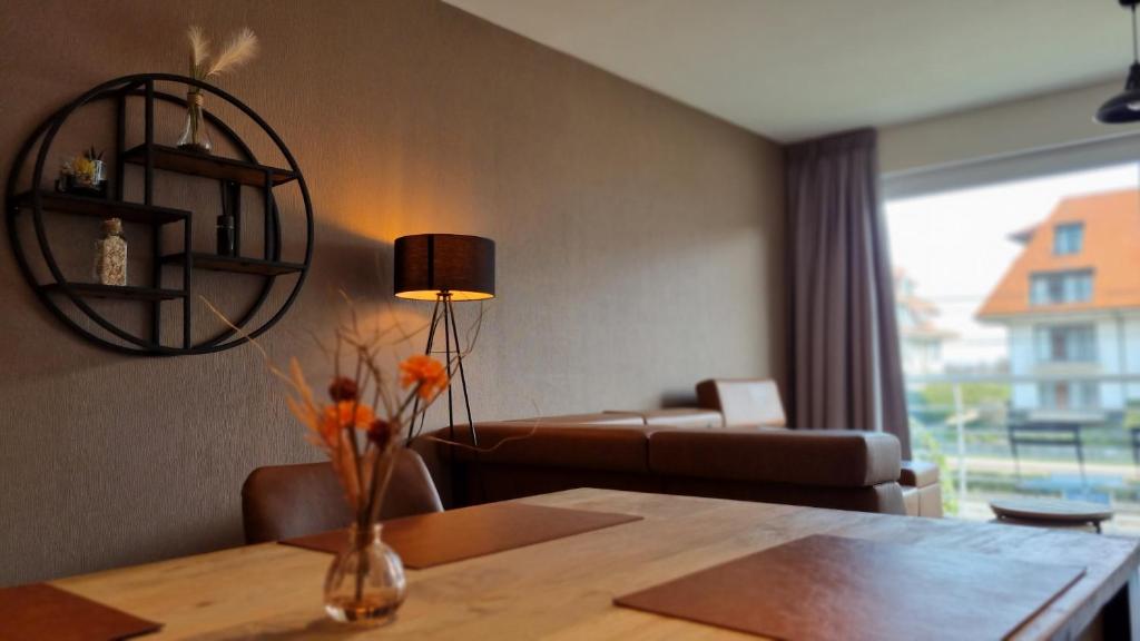 um quarto com uma mesa e uma sala de estar com um sofá em Sans Souci - residentie Neoportus em Nieuwpoort