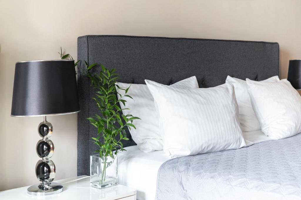 a bed with white pillows and a lamp on a table at Old Town by Welcome Apartment in Gdańsk