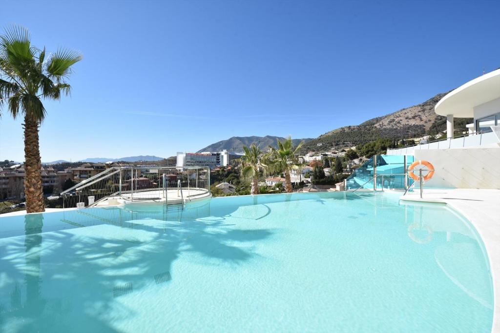 a large swimming pool with a palm tree on a building at HigueronRentals Hill Manon in Benalmádena