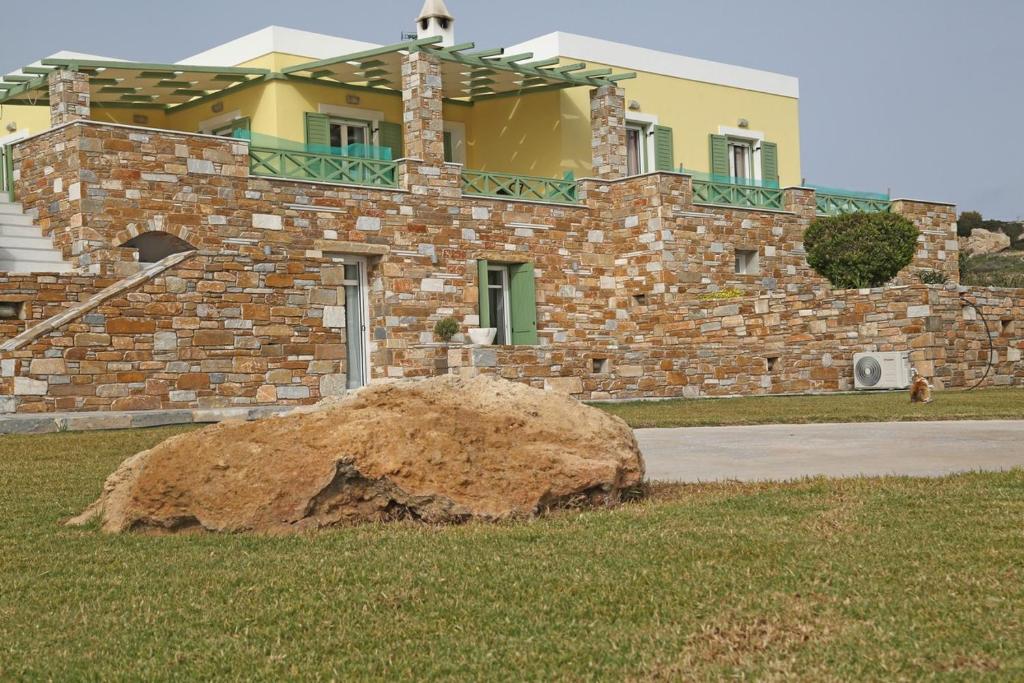 Un grand rocher dans l'herbe devant un bâtiment dans l'établissement Olea Suite Syros - Φοίνικας, Σύρος, Κυκλάδες, à Posidhonía