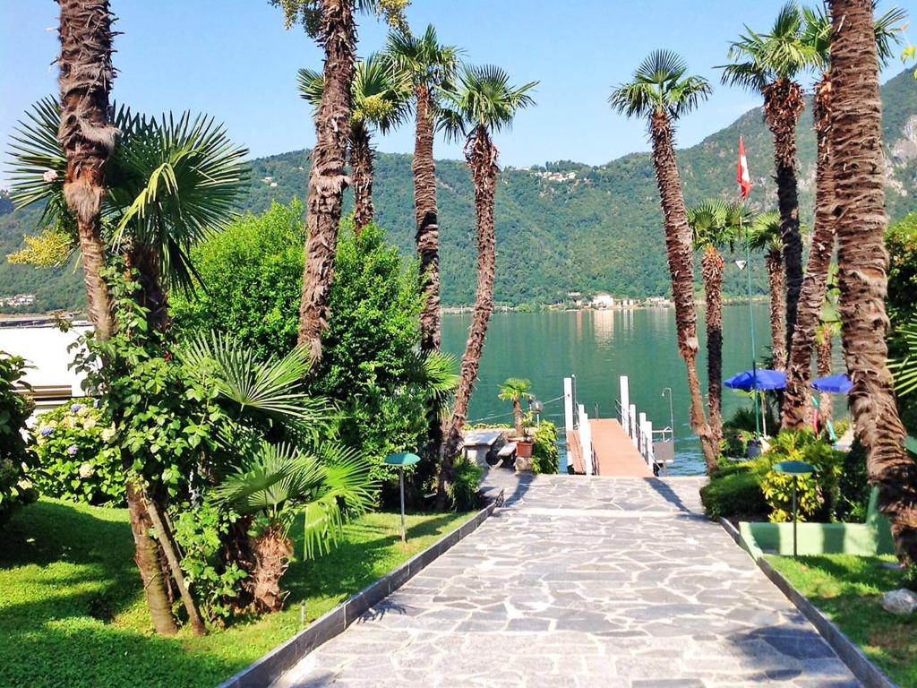 a walkway lined with palm trees next to a lake at Apartment Charming Gardenview App- 102 by Interhome in Bissone