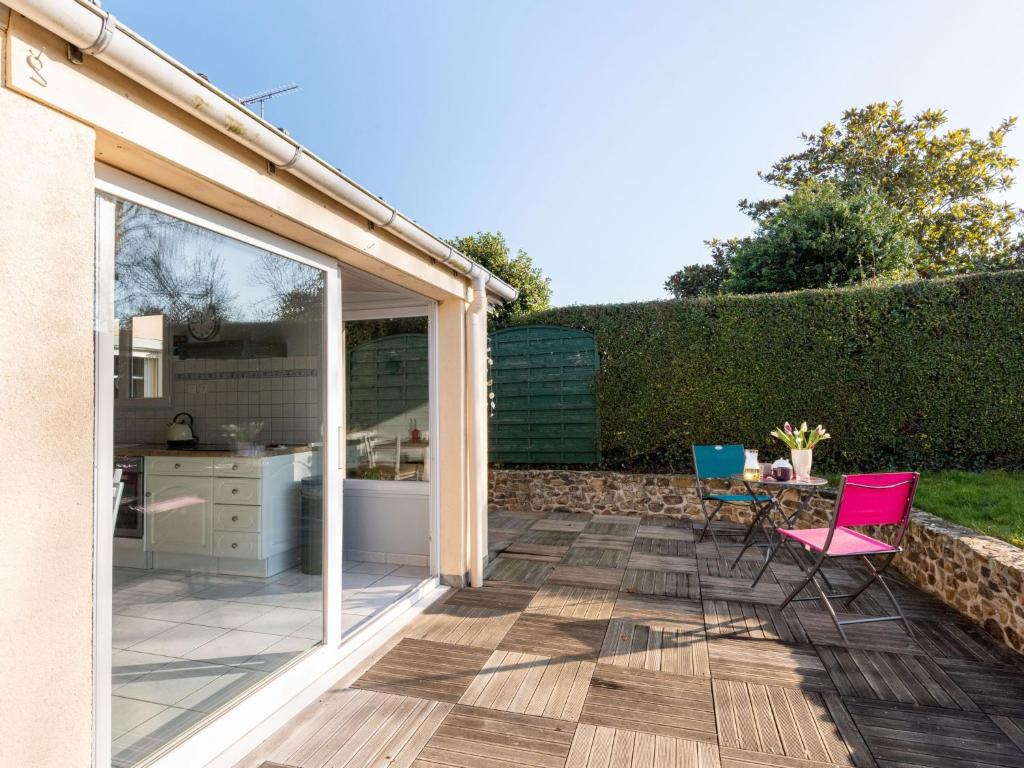 a patio with a sliding glass door and chairs at Holiday Home La petite maison by Interhome in Gouville-sur-Mer