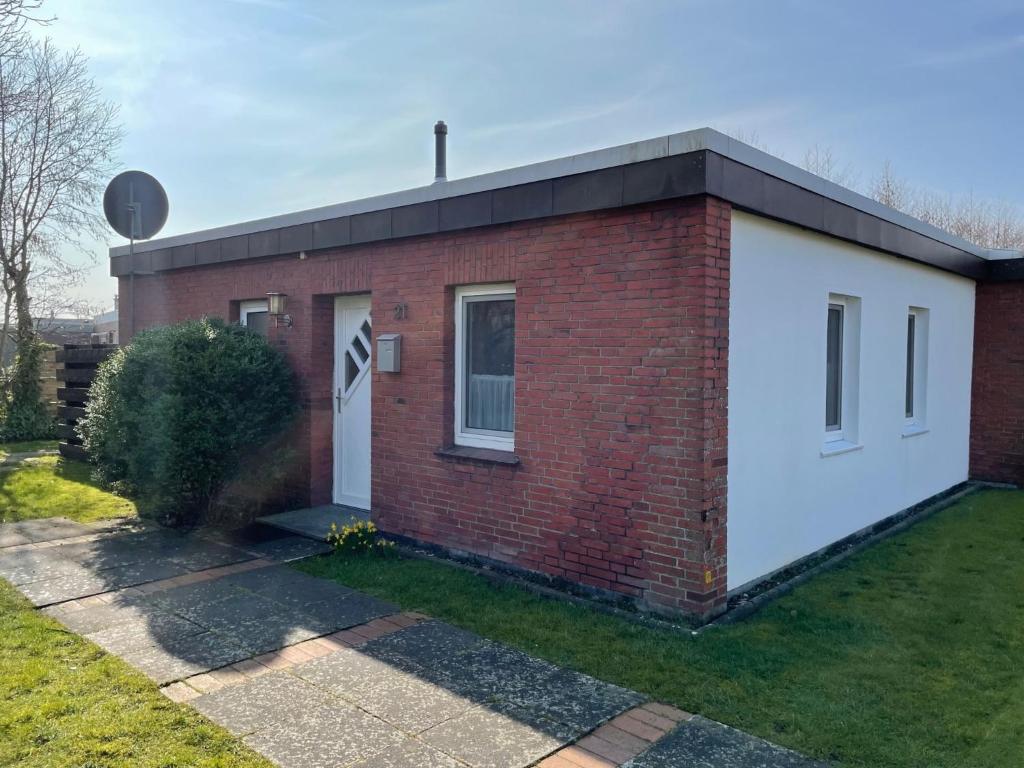 a red brick house with a white door at Holiday Home Kiel by Interhome in Norddeich