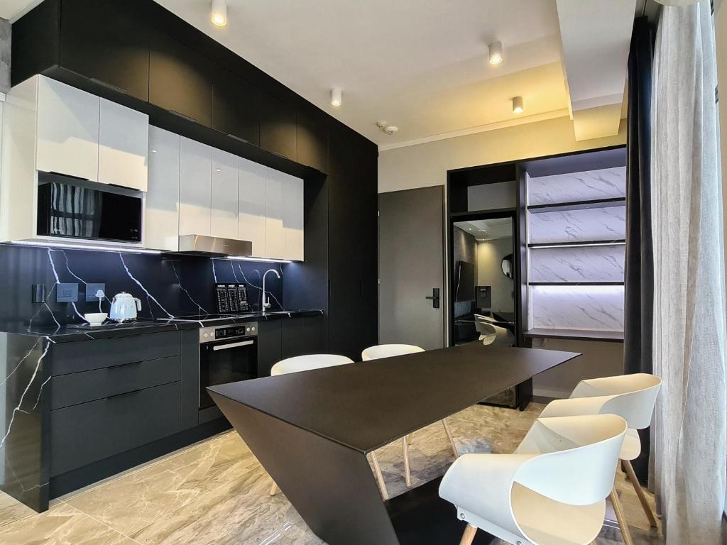Una cocina negra con sillas blancas y una mesa. en Luxurious Menlyn Maine 1 Bedroom on 12th Floor with Stunning Views & No Load Shedding, en Pretoria
