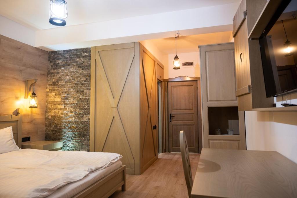 a bedroom with a bed and a table and a kitchen at Pension Mama Cozonacilor in Bran