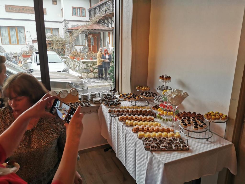 a woman taking a picture of a table full of cupcakes at Pension Mama Cozonacilor in Bran
