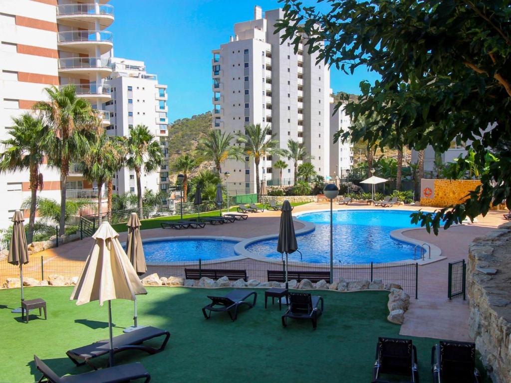 una piscina con sedie, ombrelloni e edifici di Apartment Torre Mestral by Interhome a Cala de Finestrat