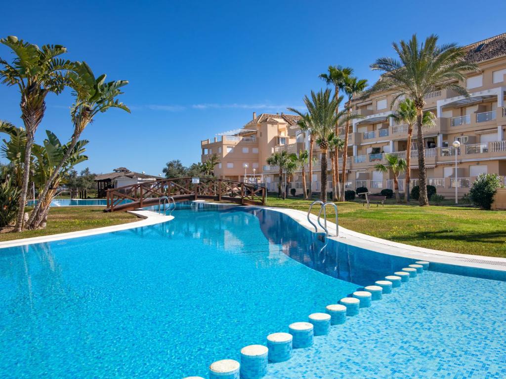 a large swimming pool with palm trees and buildings at Apartamento Tamarindo - Ubicación Premium Frente a la Playa con Piscina in Denia