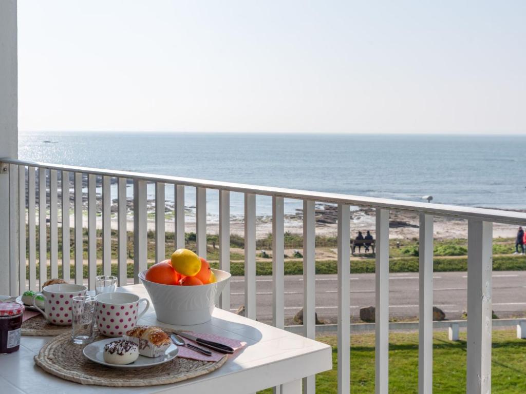 a table with a bowl of fruit on a balcony overlooking the beach at Apartment Les Trois Iles-10 by Interhome in Quiberon