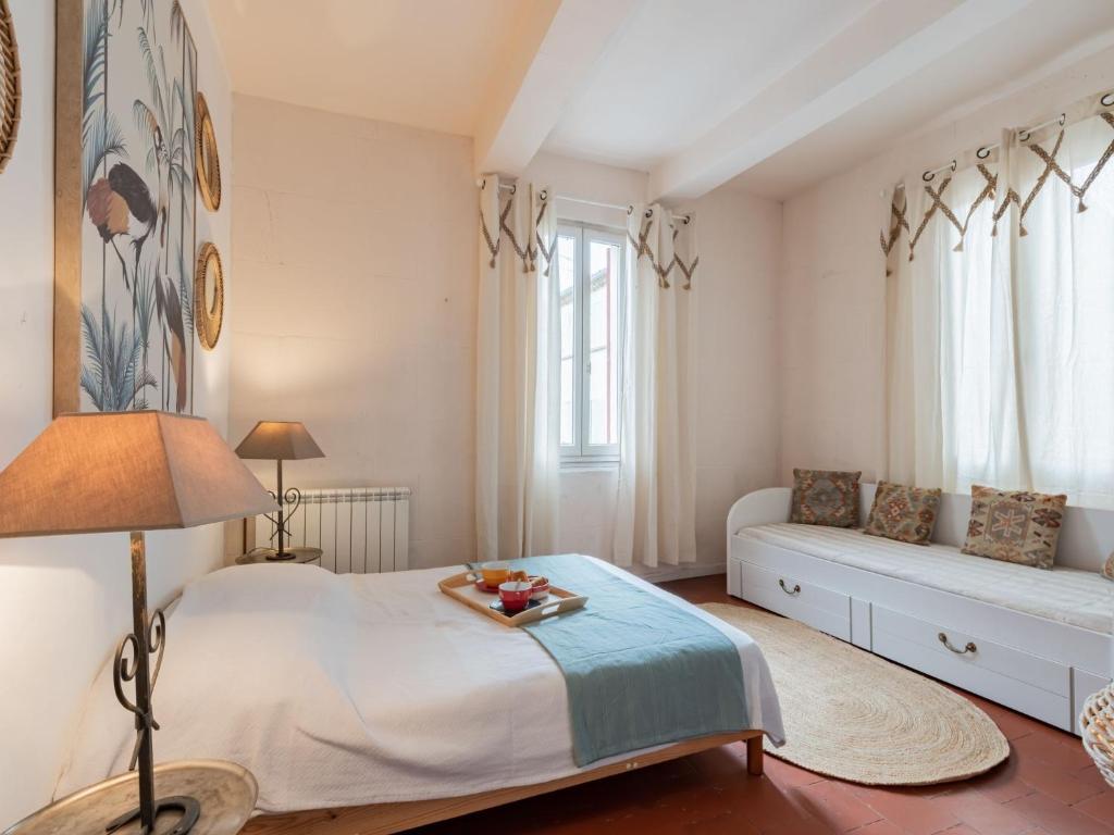 a bedroom with a bed and a couch and windows at Holiday Home La Maison Theaulon by Interhome in Aigues-Mortes
