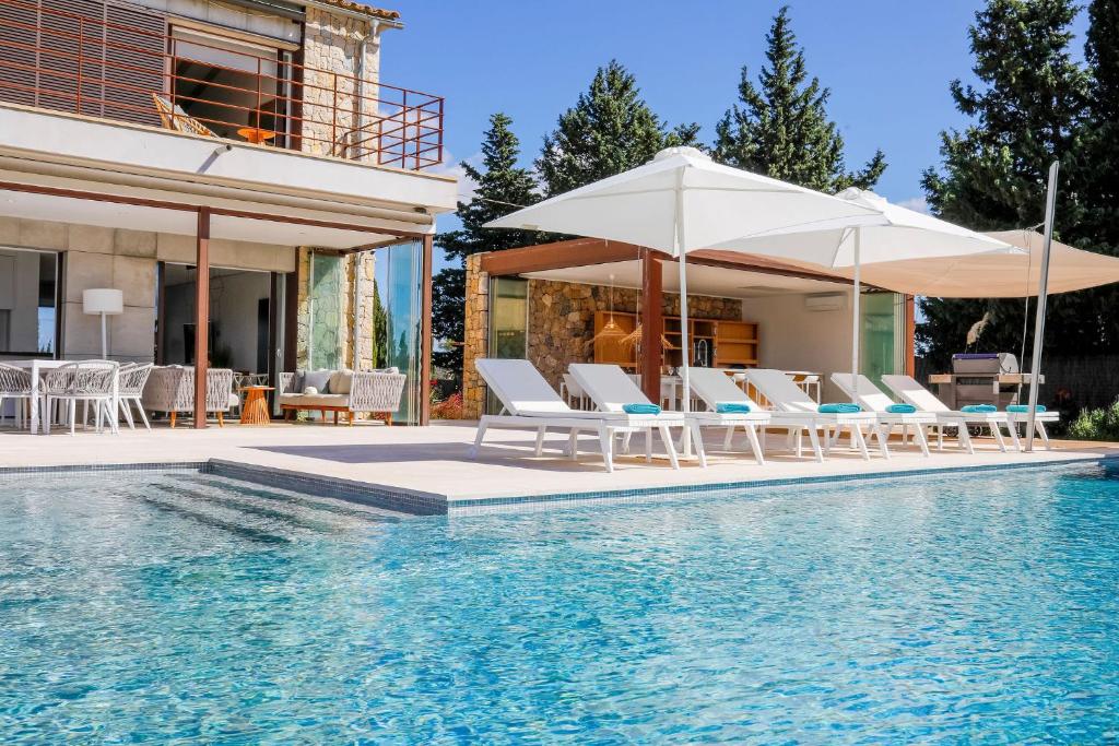 een zwembad met stoelen en parasols naast een huis bij Villa SON SET in Costitx