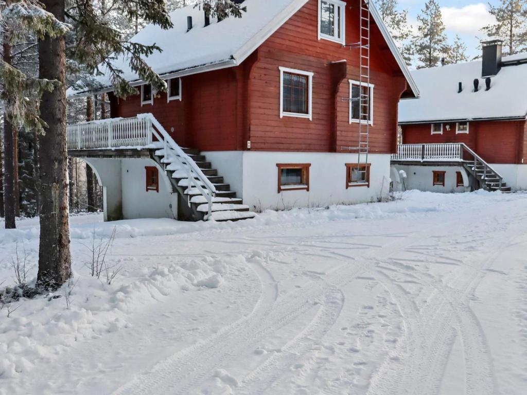 a red barn in the snow with snow tracks in the driveway at Holiday Home Alppikylä 8b paritalo by Interhome in Hyrynsalmi