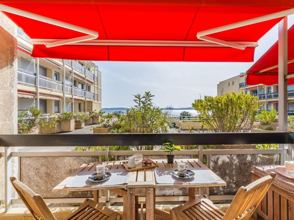 d'une table et de chaises sur un balcon avec un parasol rouge. dans l'établissement Apartment Le Grand Large-4 by Interhome, à Sainte-Maxime