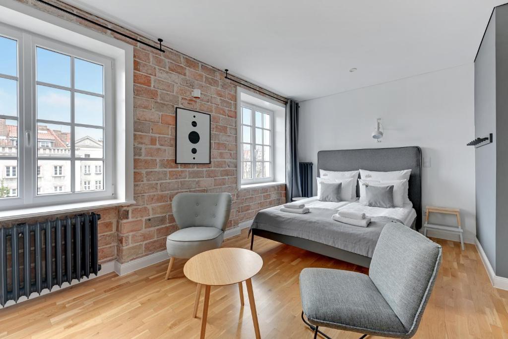a bedroom with a brick wall and a bed and a chair at Downtown Apartments Old Town Szeroka in Gdańsk