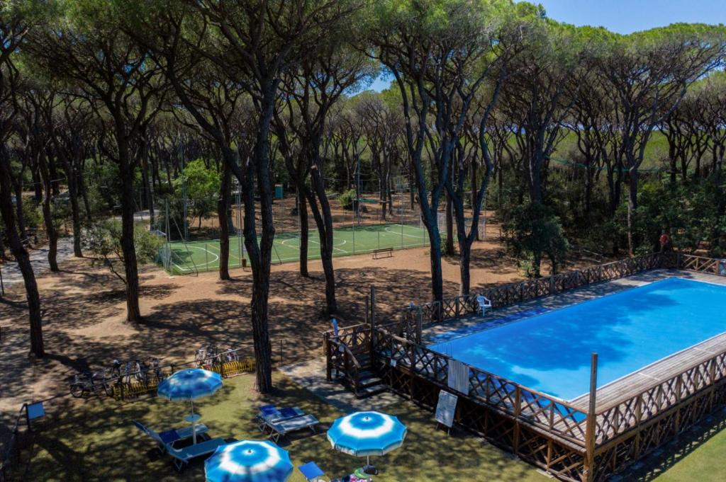 an overhead view of a pool with umbrellas and a tennis court at Comfort Lodge Maremma in Grosseto