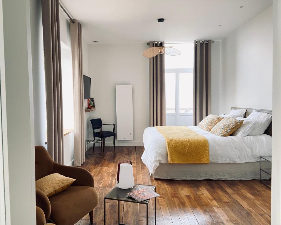 een witte slaapkamer met een bed en een bank bij La Cour Tellier in Rilly-la-Montagne