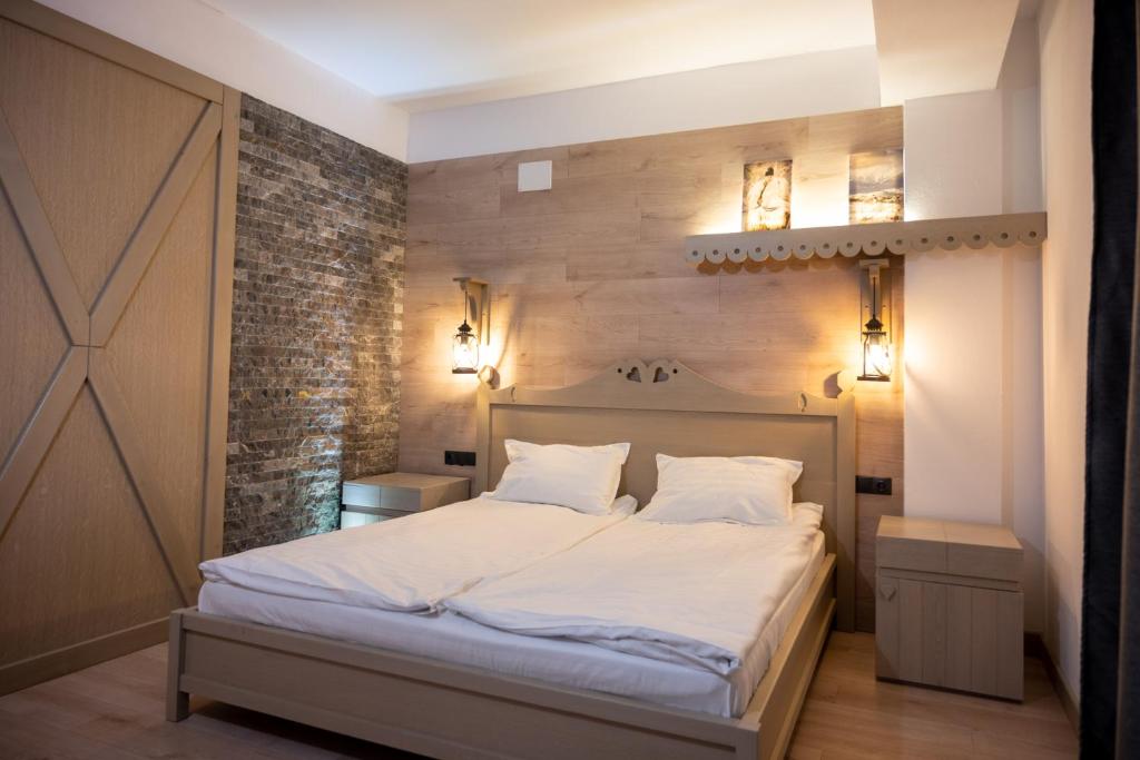 a bedroom with a bed with white sheets and a brick wall at Pension Mama Cozonacilor in Bran
