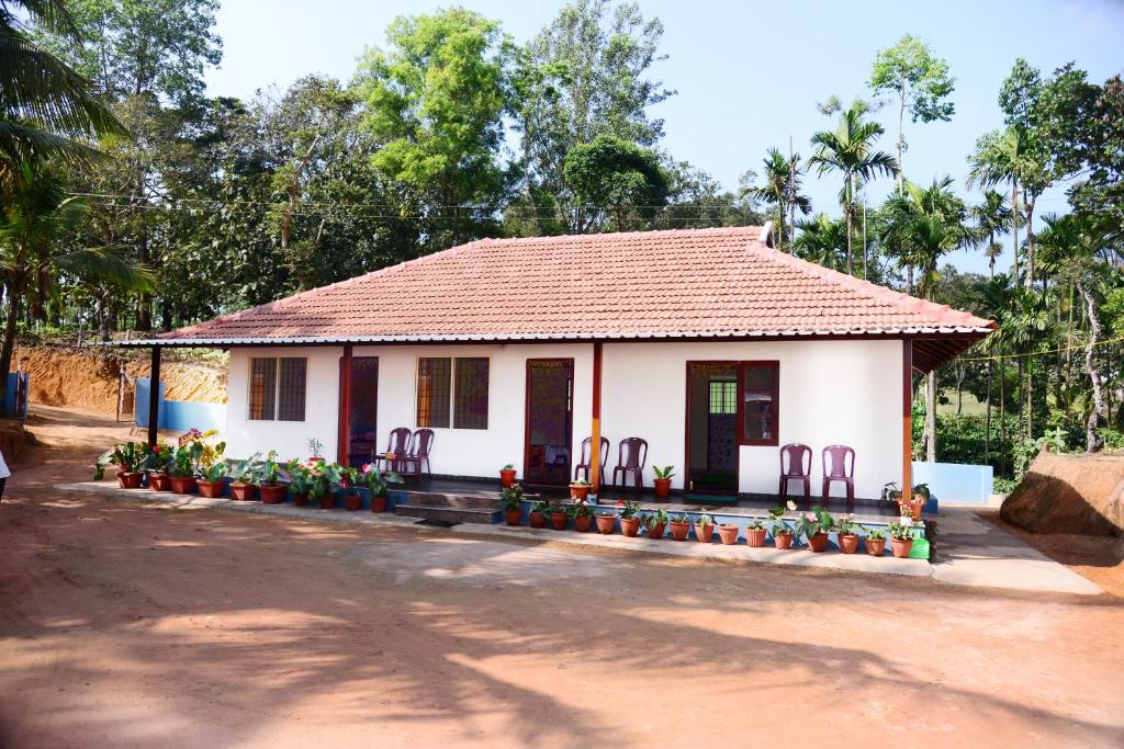 a small white house with chairs and flowers at BlueMoon Homestay - Near to falls & Trekking in Sakleshpur