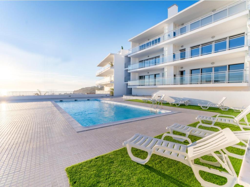 een villa met een zwembad en 2 ligstoelen bij T3 Pelican Bay in Nazaré