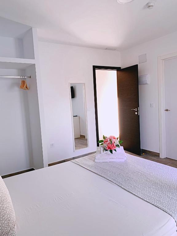 Habitación blanca con cama y espejo en Hostal El Castillo Alcala De Guadaira, en Alcalá de Guadaira