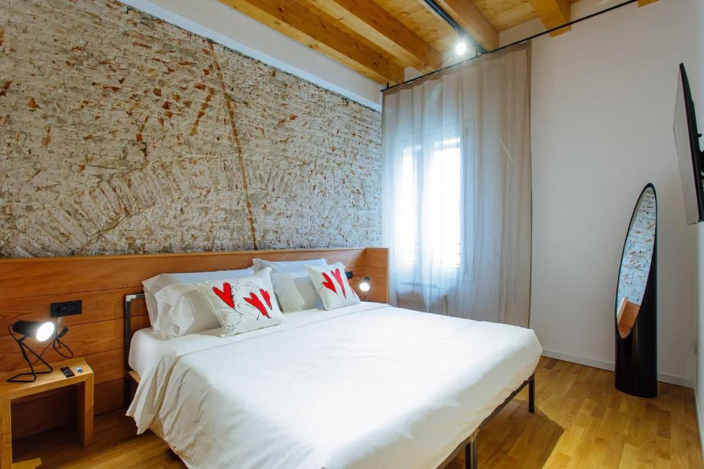 a bedroom with a white bed and a brick wall at Dadi Home Camera 1 in Padova