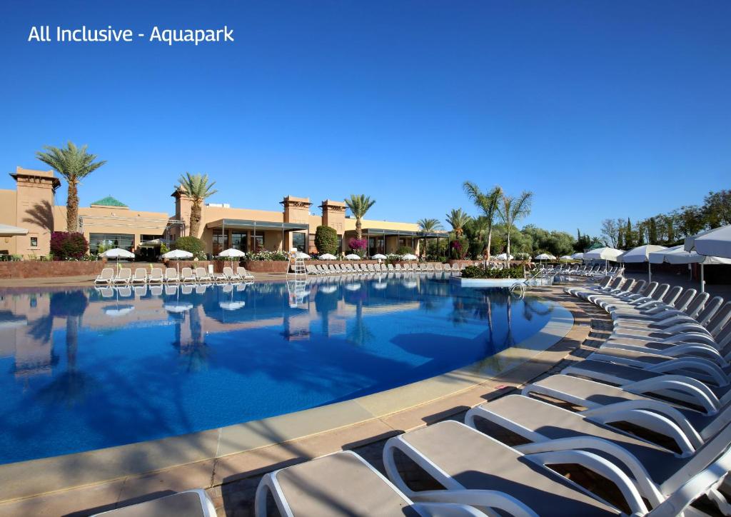 a large swimming pool with lounge chairs and umbrellas at Valeria Dar Atlas All Inclusive in Marrakesh