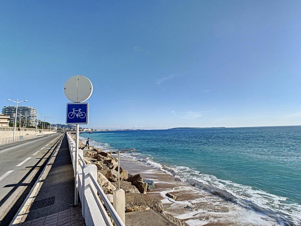 une route à côté de l'océan avec un panneau vélo dans l'établissement Duplex 6 à 7 personnes, 100 m des plages du midi, Cannes, à Cannes