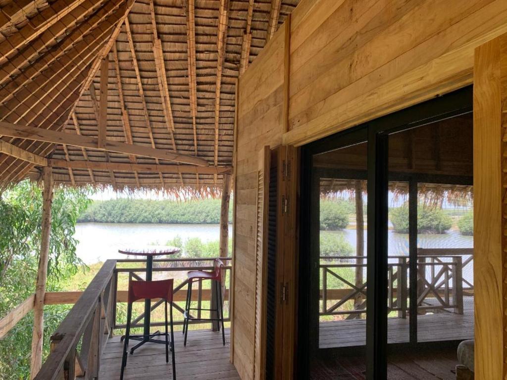 a wooden house with a deck with a table and chairs at Natura luxury camp in Ouidah