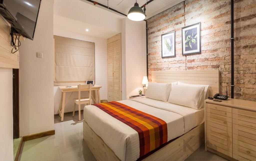 a bedroom with a large bed and a desk at Blackout Boutique Hotel in Colombo