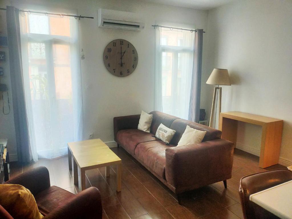 un salon avec un canapé et une horloge au mur dans l'établissement T3 proche Castillet, à Perpignan