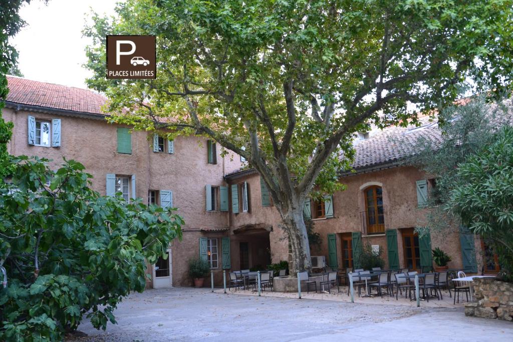 a building with chairs and a tree in front of it at Hôtel Saint Jean in Orange